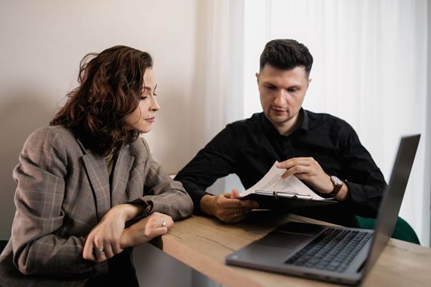 A person and person sitting at a table with a computer